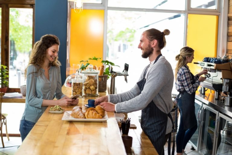 Waiter serving a cup of coffee to customer at counter